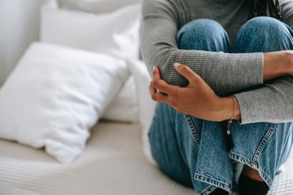 Image of woman folding her arms over her legs in a worried pose. This represents the stress we sometimes feel from dating and relationships that makes us want to give up on dating.